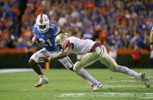 Nov 28, 2015; Gainesville, FL, USA; Florida Gators running back Kelvin Taylor (21) runs with the ball as Florida State Seminoles defensive end Josh Sweat (9) tackles him during the first quarter at Ben Hill Griffin Stadium. Mandatory Credit: Kim Klement-USA TODAY Sports