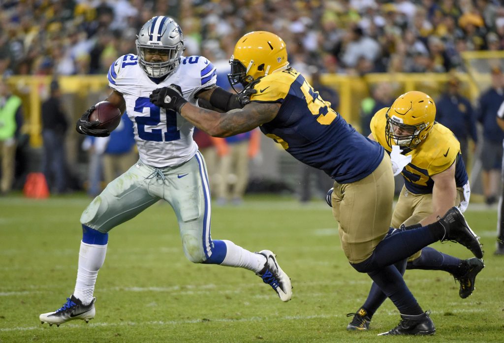 Oct 16, 2016; Green Bay, WI, USA; Dallas Cowboys running back Ezekiel Elliott (21) carries the ball as Green Bay Packers linebacker Julius Peppers (56) defends in the fourth quarter at Lambeau Field. Mandatory Credit: Benny Sieu-USA TODAY Sports