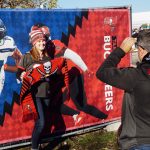 A poses for a photo in front of the rivalry poster during the NFL Fan Fest. Scarves that are a norm for soccer games made their way to the Allianz Arena as an American football accessory.