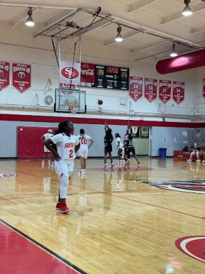 A Santa Fe basketball player looks at the scoreboard, unhappy, as a Columbia player makes a free throw behind her.