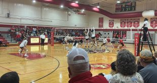 Two Bishop Moore players attempt to block the ball as it crosses over the net