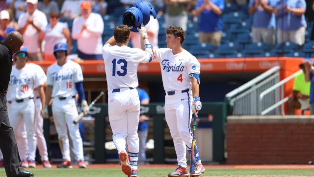 Landon Stripling (left) and Cade Kurland (right) tap helmets at home plate after Stripling homered to center field in the sixth inning. (Photo by Ryan Scarane/WRUF)